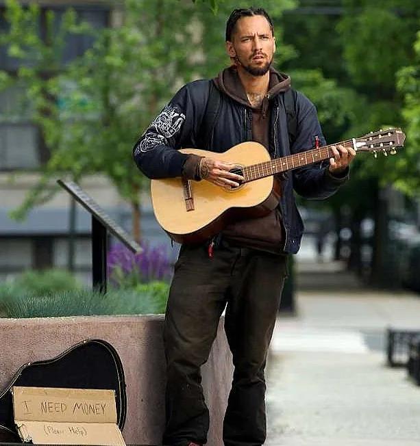 Jonathan seen singing his father's song with a sign, I Need Money